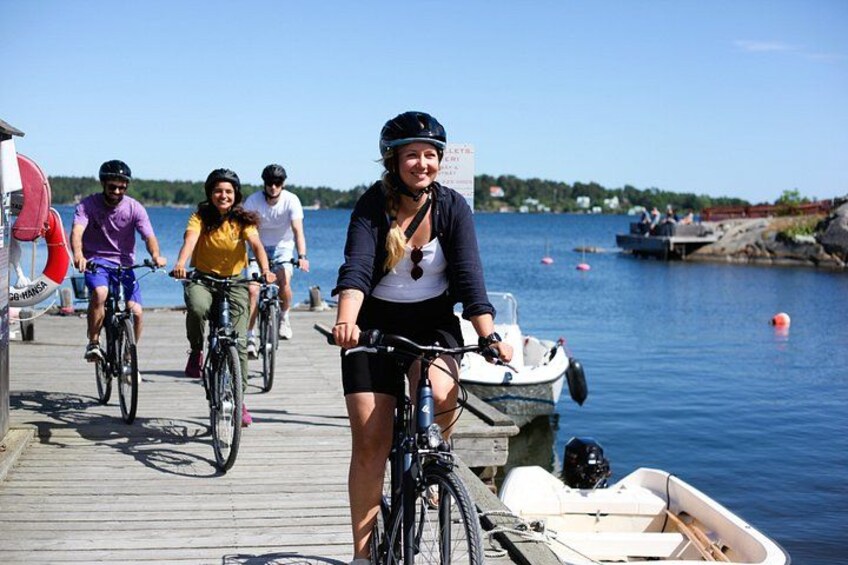 A group of people on bicycles on a wooden dock by a body of water. 1