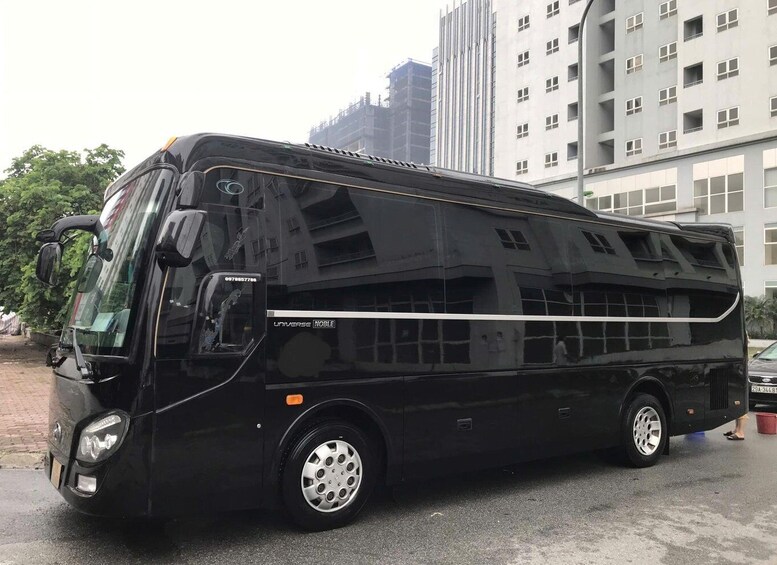 A black bus with 'UNIVERSE NOBLE' branding parked in an urban setting with buildings in the background. 4