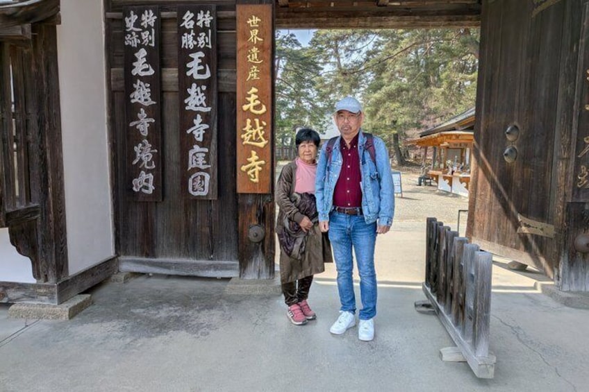 A wooden gate with Japanese characters, a paved path, and a building in the background. 1