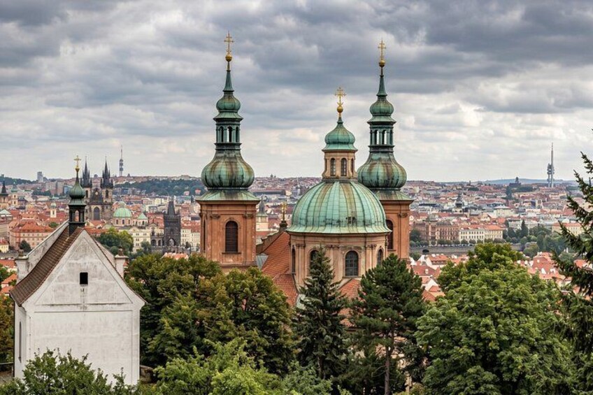A cityscape with prominent green domed buildings and a white structure in the foreground. 4