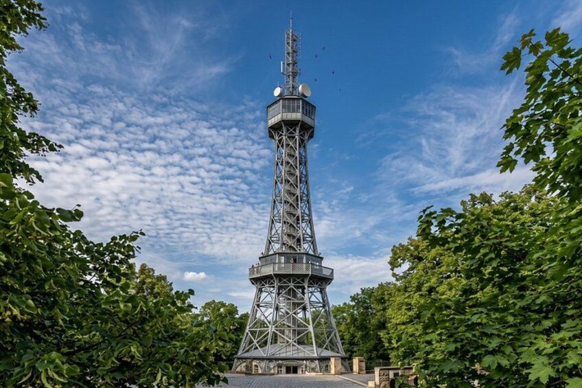 A tall tower with a lattice structure, surrounded by trees and a clear sky. 1