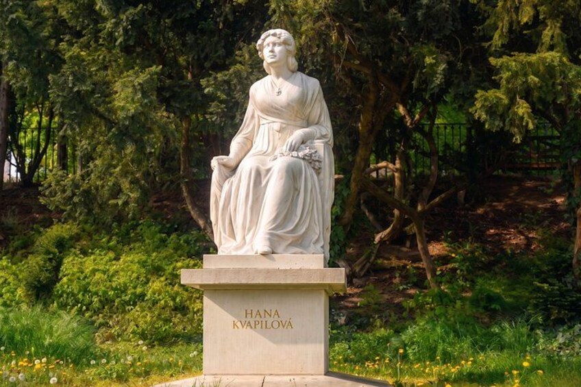 A statue of a woman in a white dress, labeled 'HANA KAPILOVAN,' set in a park with trees and grass. 3