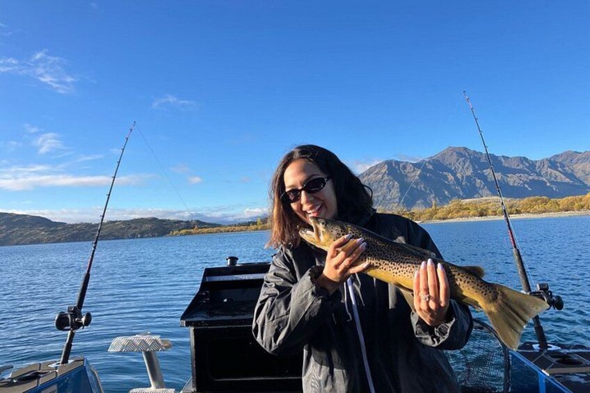 A person holding a fish on a boat with mountains in the background. 3