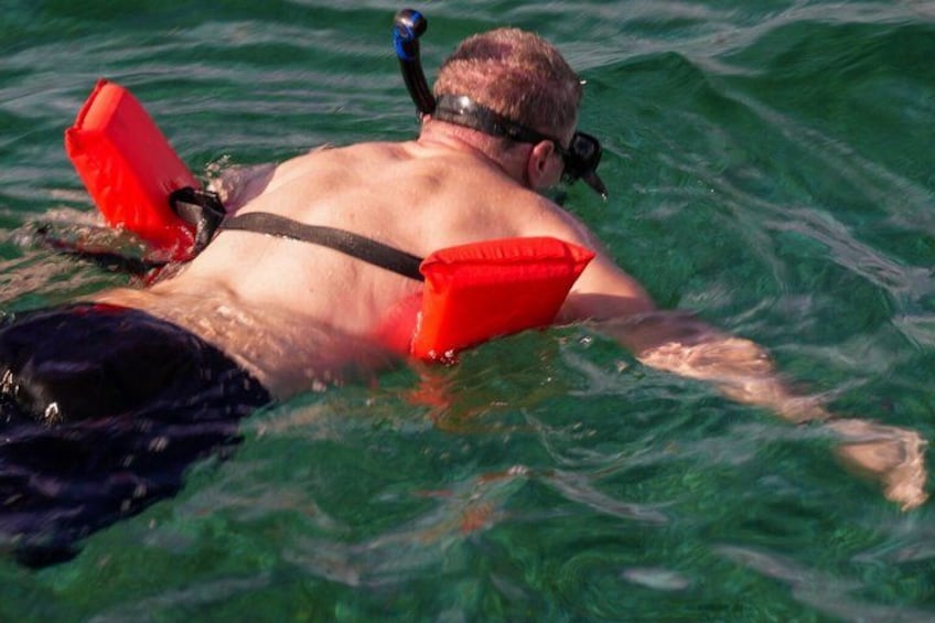A person swimming with red flotation devices. 2