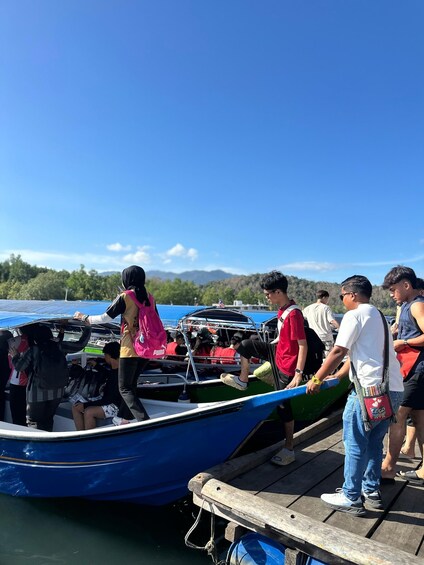A group of people boarding a blue boat at a dock. 1