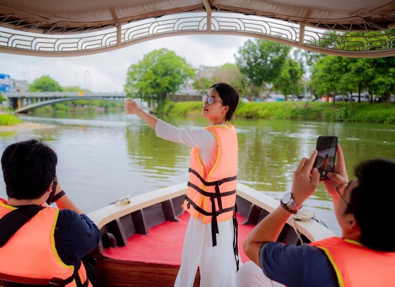 A boat tour with a guide pointing towards a bridge in the background. 2