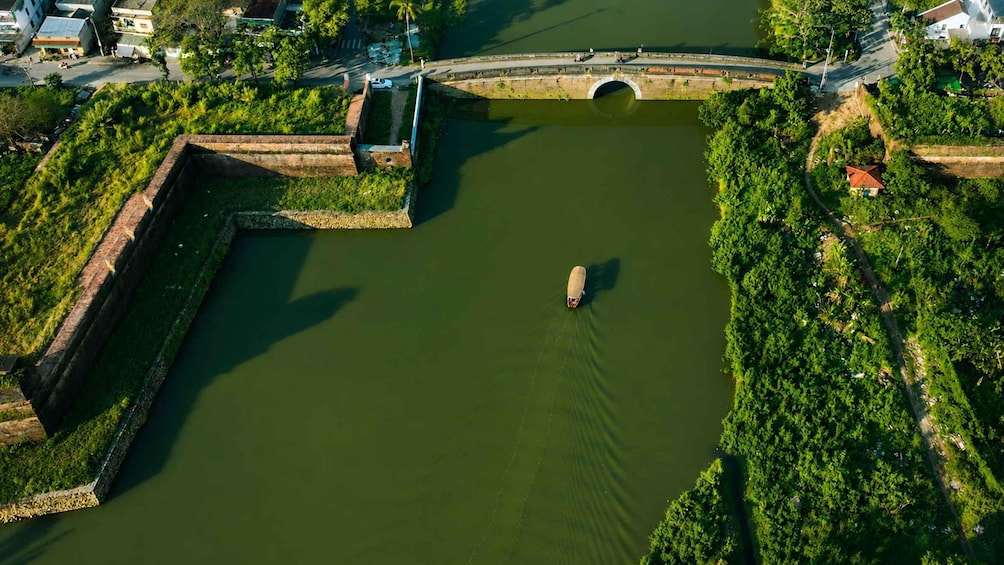 A river with a boat, a bridge, and surrounding greenery. 1