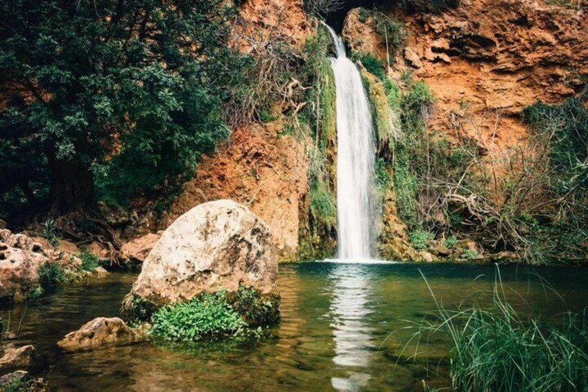 A waterfall, a large rock, and a river. 1