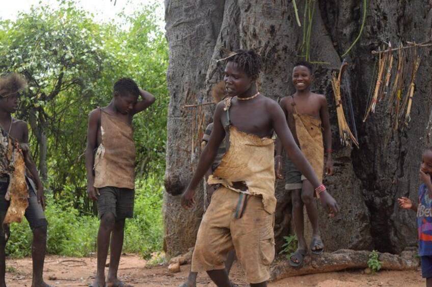 A group of people in traditional attire near a large rock formation. 1