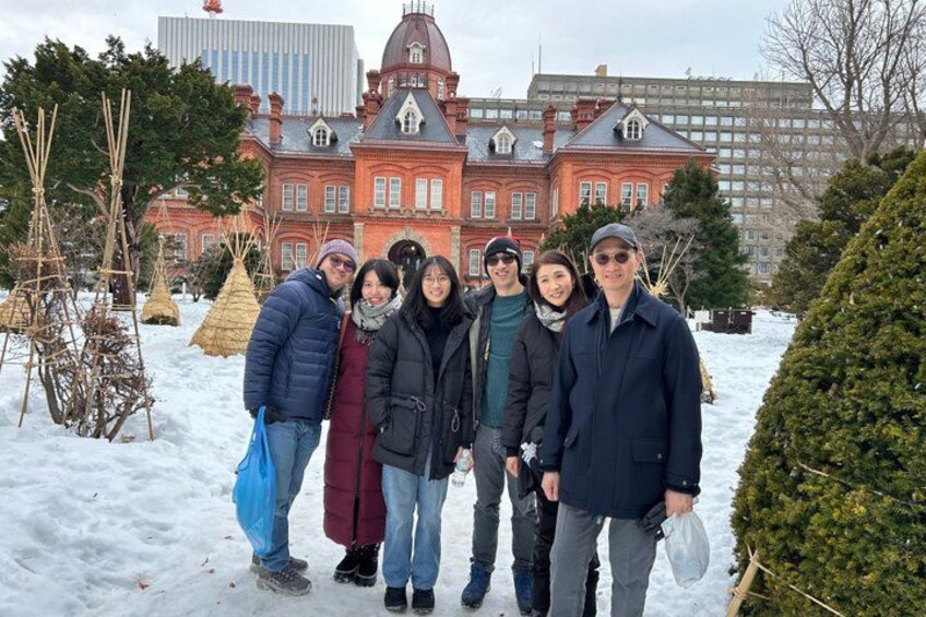 Un grupo de personas en una zona nevada, con un edificio rojo grande al fondo. 2