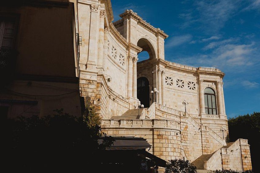 A historic building with a prominent archway, detailed stonework, and a clear blue sky. 4