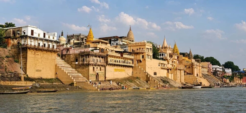 A riverside cityscape with historic architecture, including domed buildings and a large staircase leading to a temple. 2