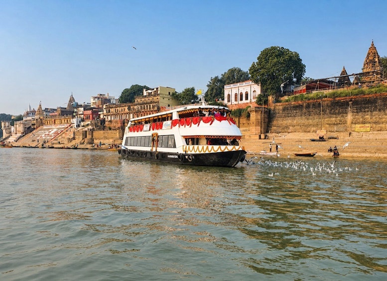 A riverboat with passengers, a temple, and a cityscape along the riverbank. 1