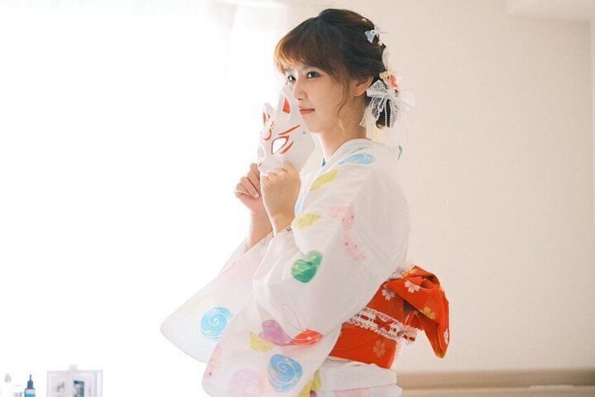 A person in a white robe with colorful patterns, holding a red object. 2