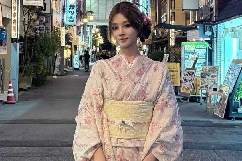 A person in a kimono standing on a street with shops and signs in the background. 3
