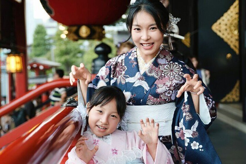 A person in a kimono with a child in a pink outfit on a red vehicle. 5