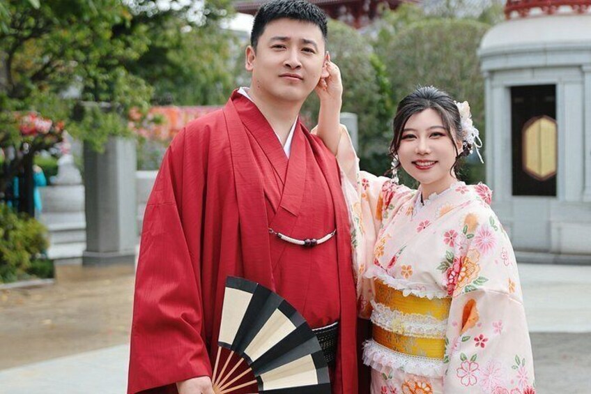 A person in a red traditional outfit holding a fan, standing next to someone in a floral kimono. 4