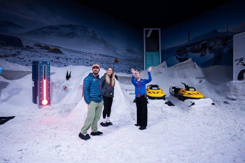 Two people in a snowy exhibit with a thermometer and snowmobiles. 5