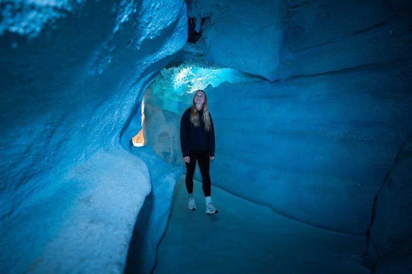 A person standing in an ice cave with blue lighting. 3