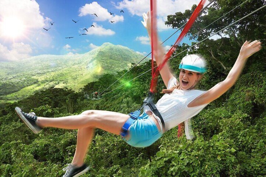 A person ziplining over a lush green landscape with mountains in the background. 1