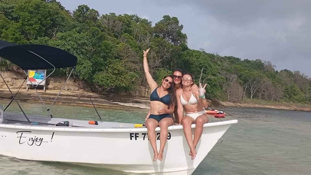 Three people on a boat with a forested shoreline in the background. 2