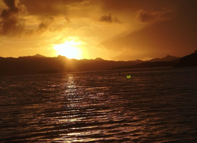 A sunset over a body of water with a silhouette of a mountain range in the background. 4