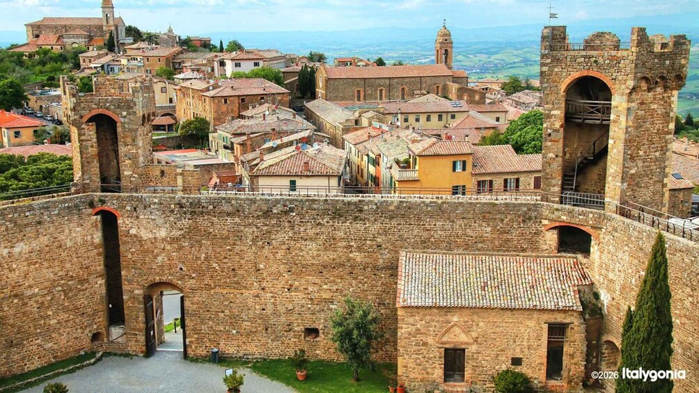A historic town with stone walls, a fortified gate, and traditional buildings. 2