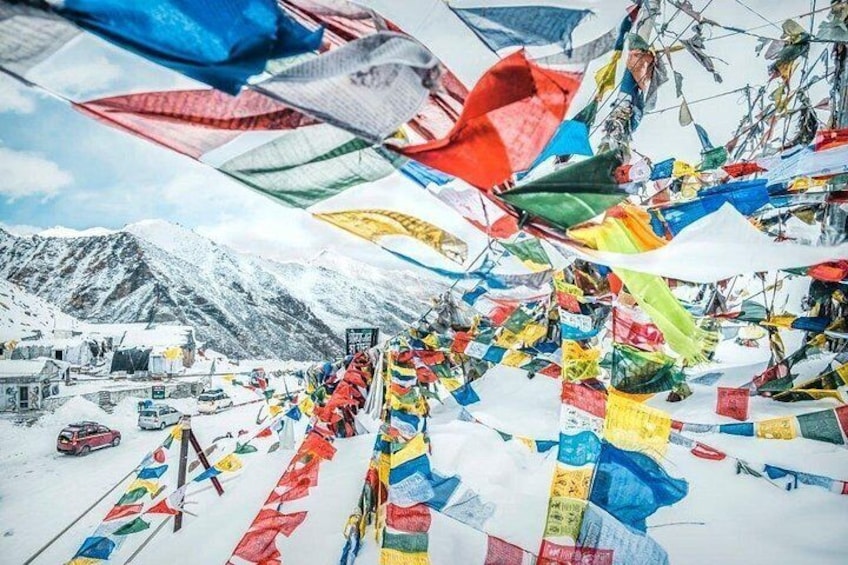 A snowy mountain landscape with colorful prayer flags and a red vehicle. 3