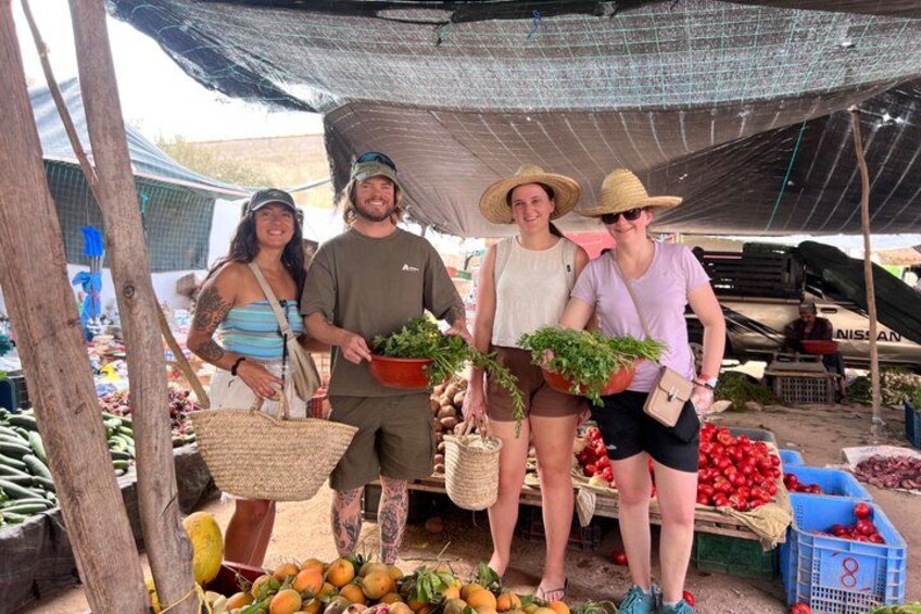 A market stall with people holding baskets of produce. 2