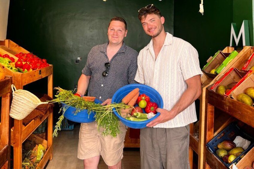 Two people holding bowls of vegetables in a market. 2