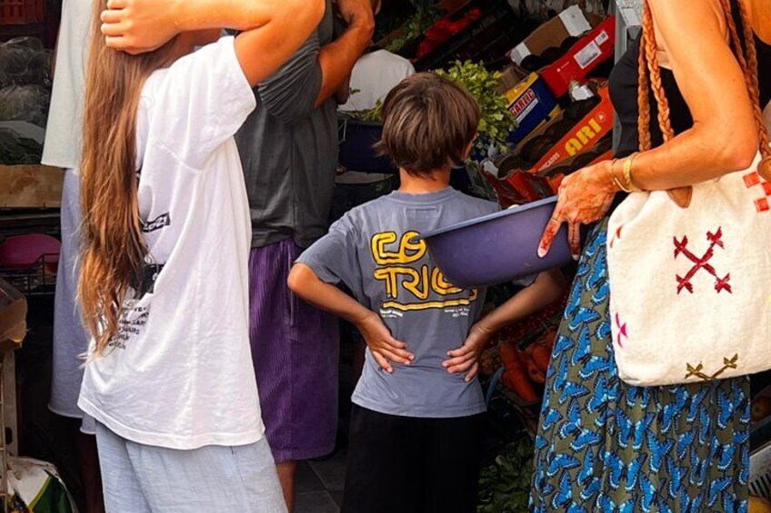 A group of people at a market stall with various goods on display. 3