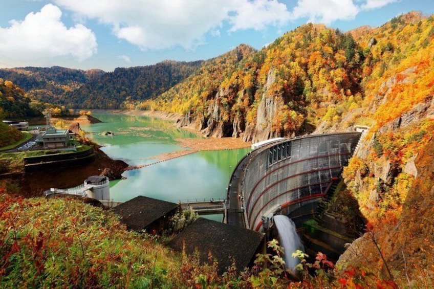A dam with a lock system, a river, and autumn-colored hills. 1