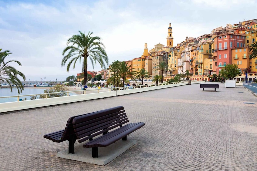 Una passeggiata sul lungomare con una panchina, palme e edifici colorati sullo sfondo. 5