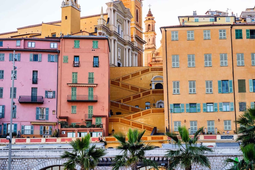 Una fila di edifici colorati con balconi, una scala e una chiesa con un campanile. 4