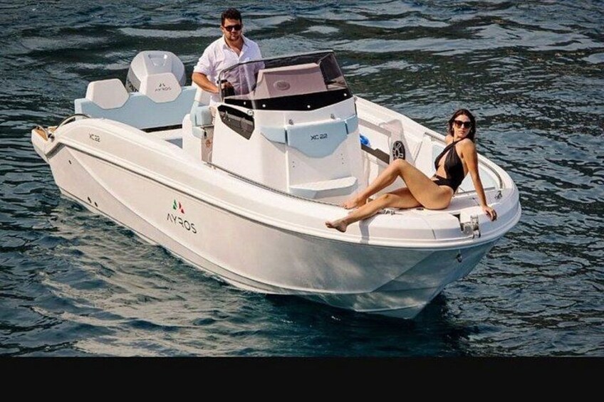 A small white motorboat on water with a woman and a man on board. 3
