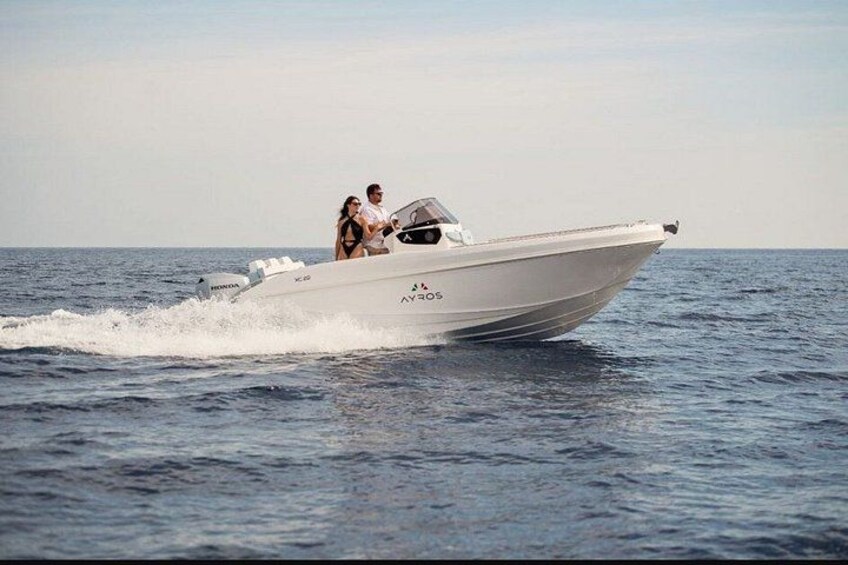 A white speedboat with two people on board, moving through the water. 2