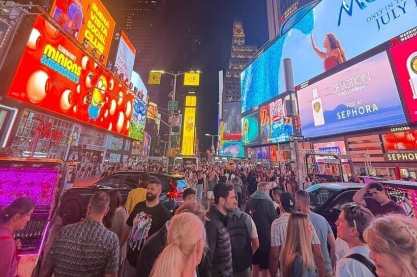 A busy urban street with illuminated billboards and storefronts. 3