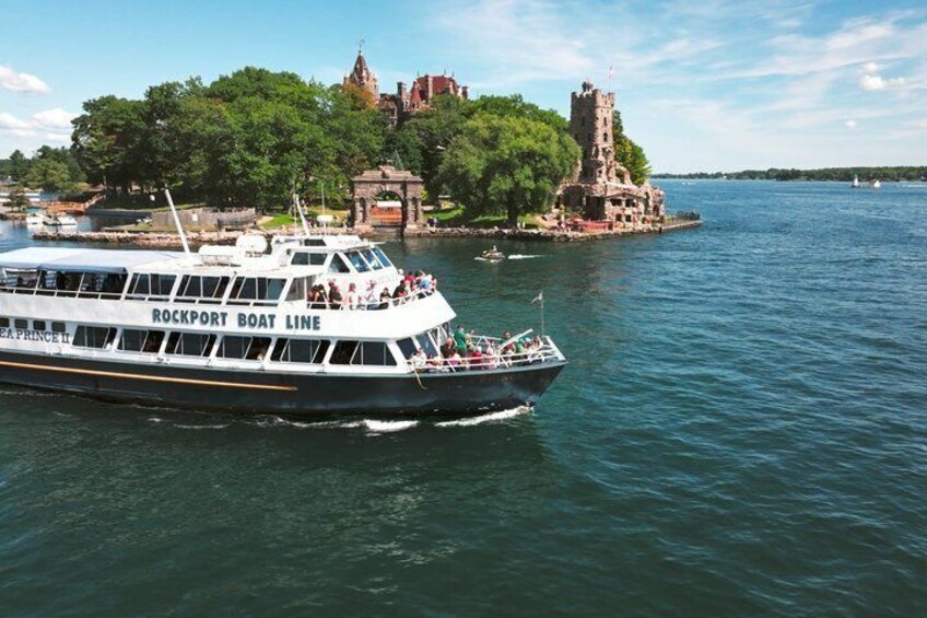 A Rockport Boat Line vessel on calm waters with a historic castle and tower in the background. 1