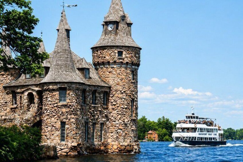 A stone castle with multiple towers by a river, with a boat in the background. 5