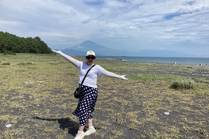 A person standing on a beach with arms outstretched, a mountain in the background, and a clear sky. 5