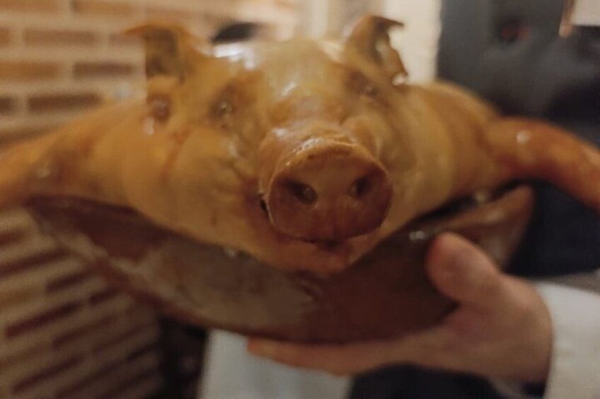 A person holding a large, cooked pig's head. 2