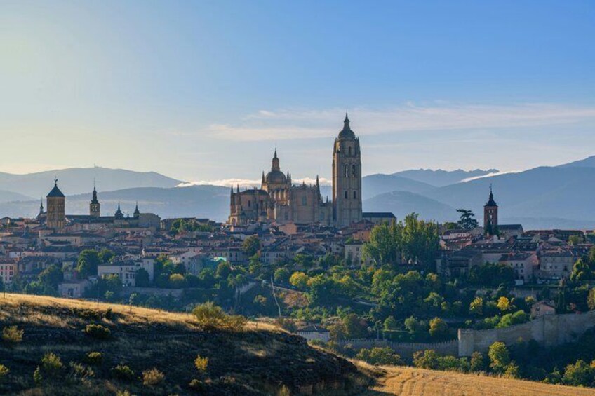 A cityscape with prominent historical architecture, including a cathedral and bell towers, set against a backdrop of mountains. 5