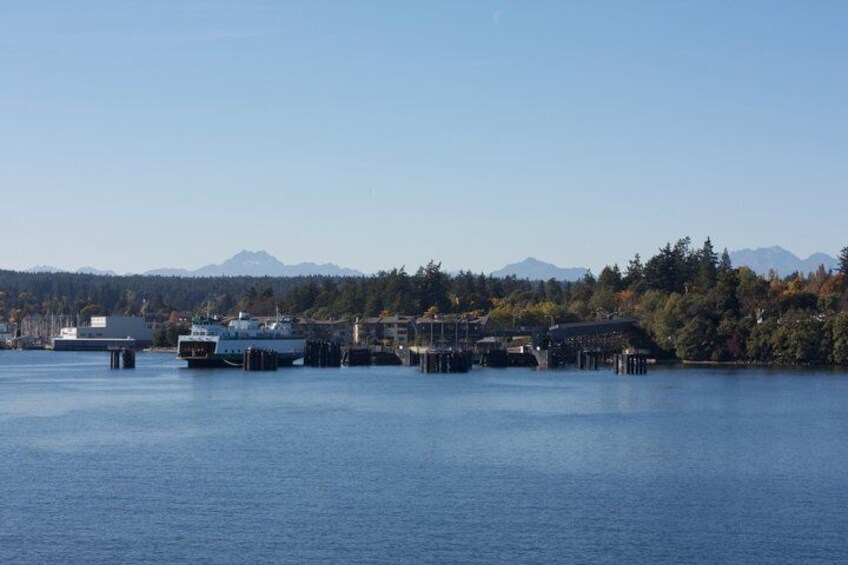 A calm lake with docked boats, a pier, and a forested mountain range in the background. 3