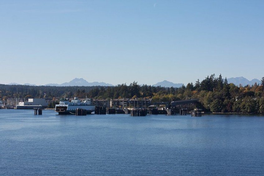 A calm lake with docked boats, a pier, and a forested mountain range in the background. 3