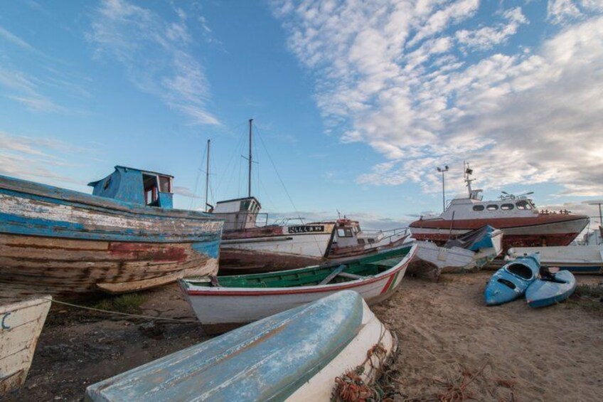 A row of boats on a sandy beach with a partly cloudy sky. 2