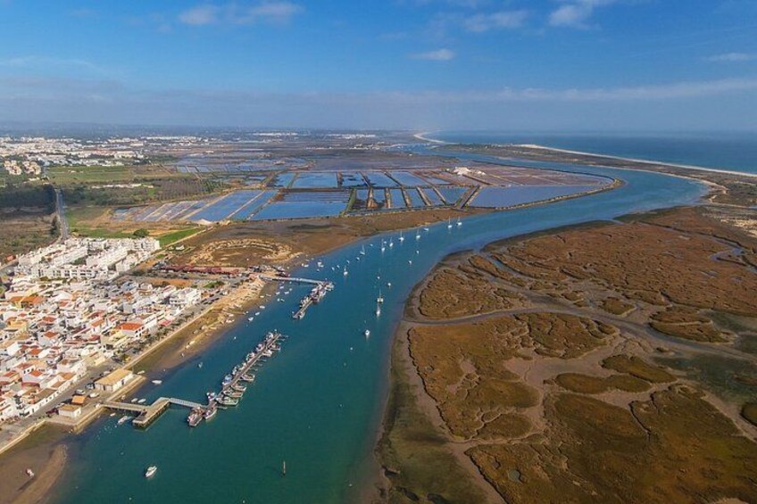 An aerial view of a coastal area with a marina, boats, and a town. 2