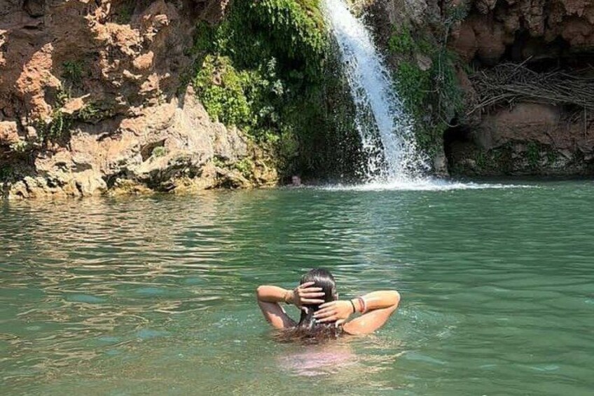 A person swimming in a body of water with a waterfall in the background. 4