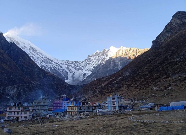 A mountainous landscape with a snow-capped peak, a valley with buildings, and a clear sky. 2