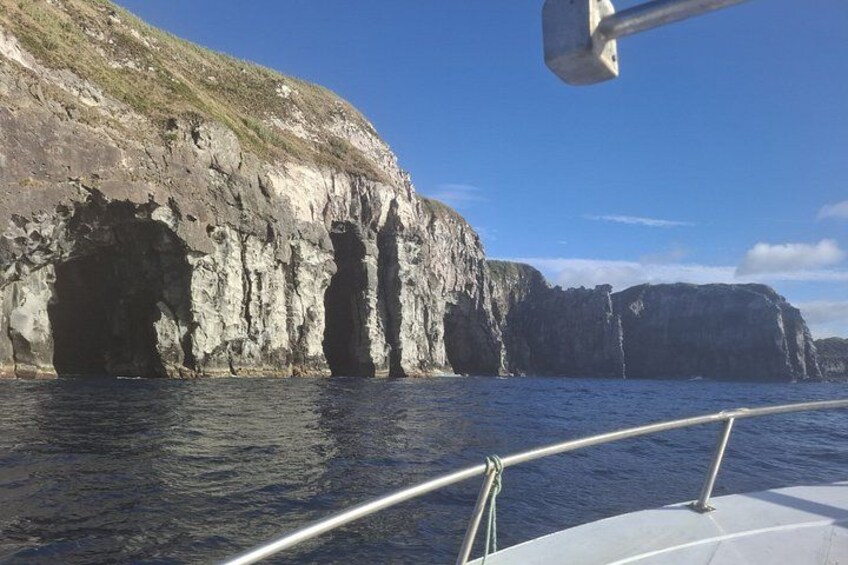 Un bateau près d’une côte rocheuse, avec une grande formation géologique ressemblant à une grotte. 2