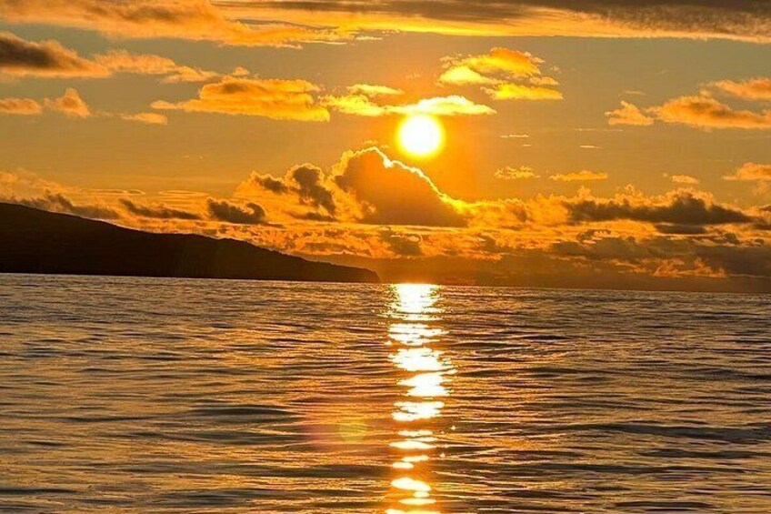 A sunset over a body of water with clouds reflecting the sun's light. 2